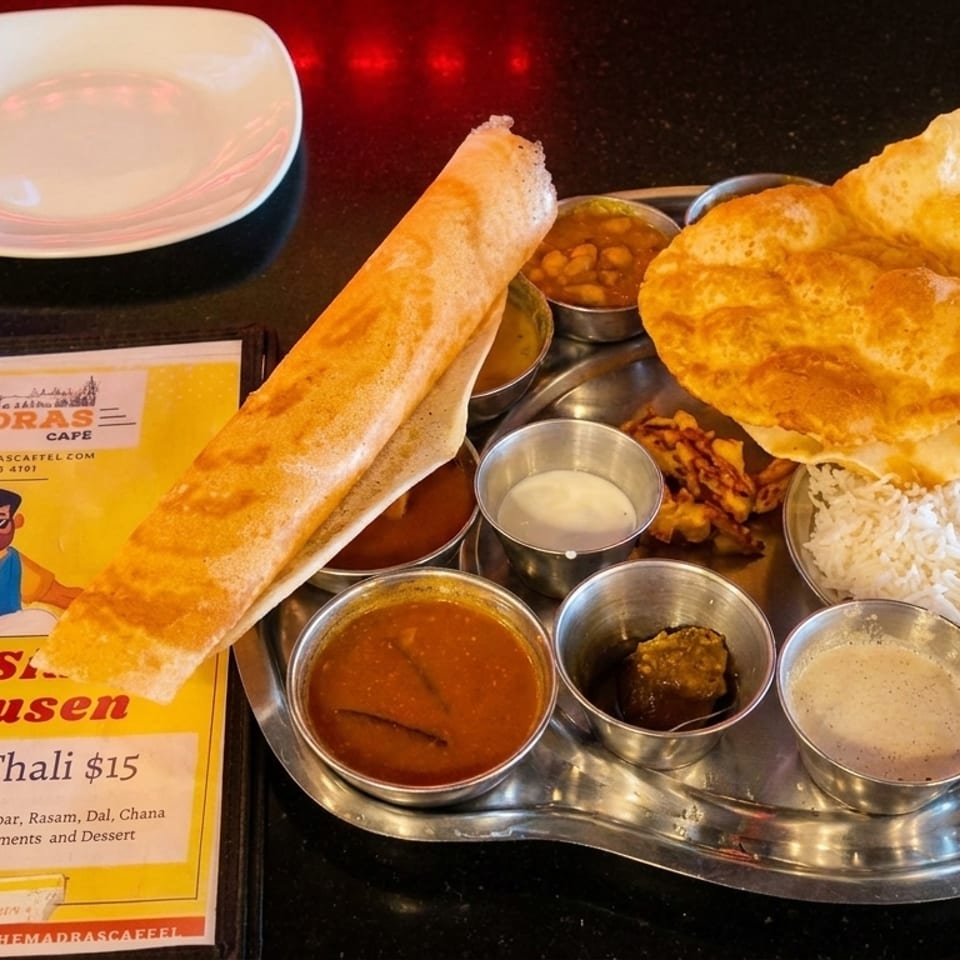 A South Indian Thali from The Madras Cafe, featuring dosa, poori, rice, and various curries.